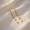 Gold star and bar drop earrings detail on fabric, AllureNL